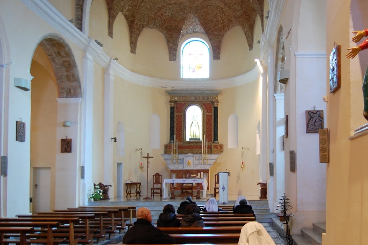 The white nave of the church of the Misericordia in Alghero, with pointed arches and a lit altar