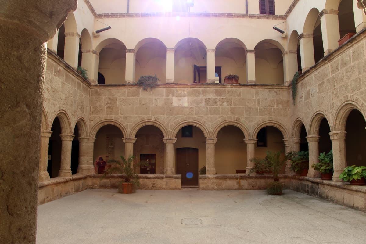 The two-storey cloister of San Francesco in Alghero, with rounded arches on sandstone columns around a courtyard