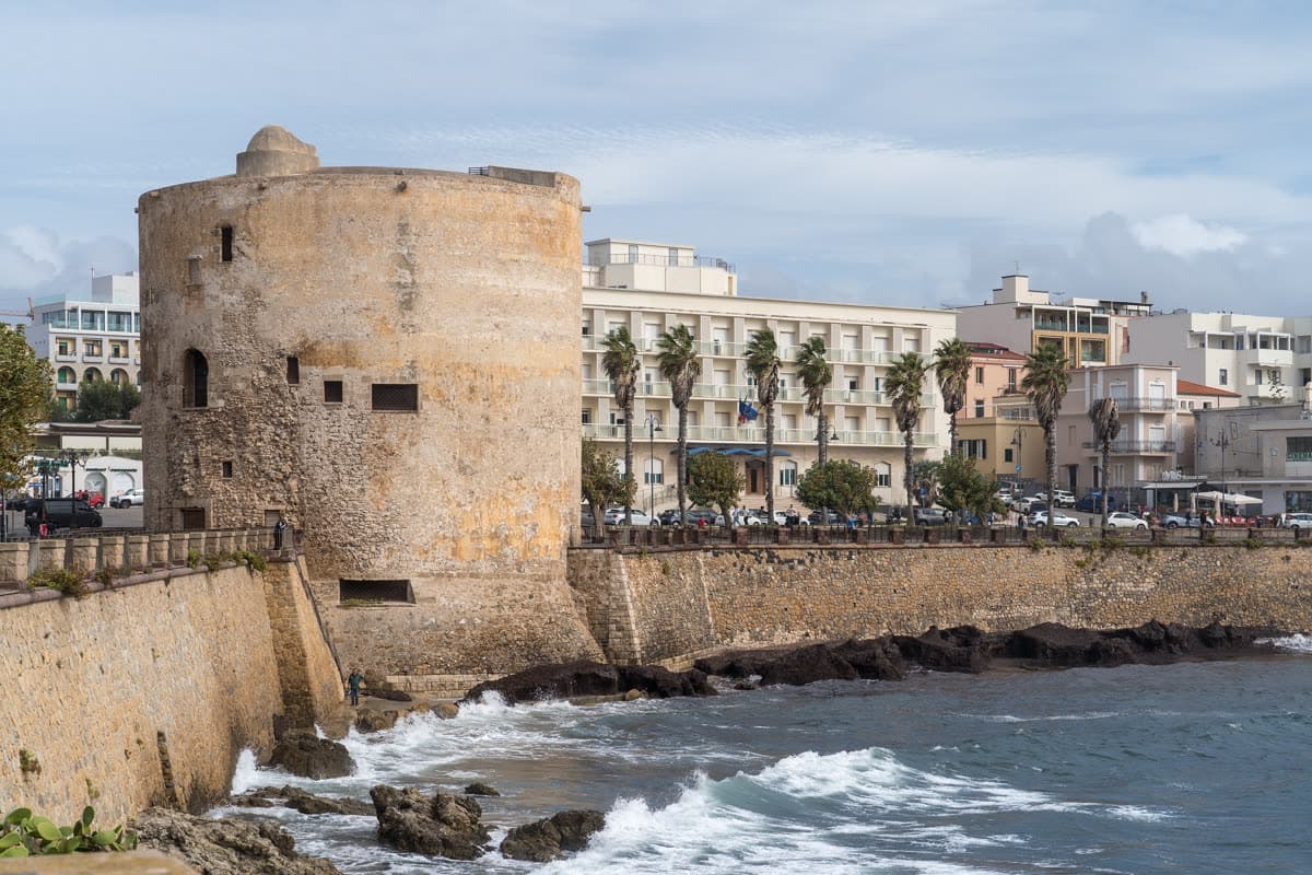 Torre di Sulis on the bastions of Alghero, a massive round tower above the sea with waves at its base