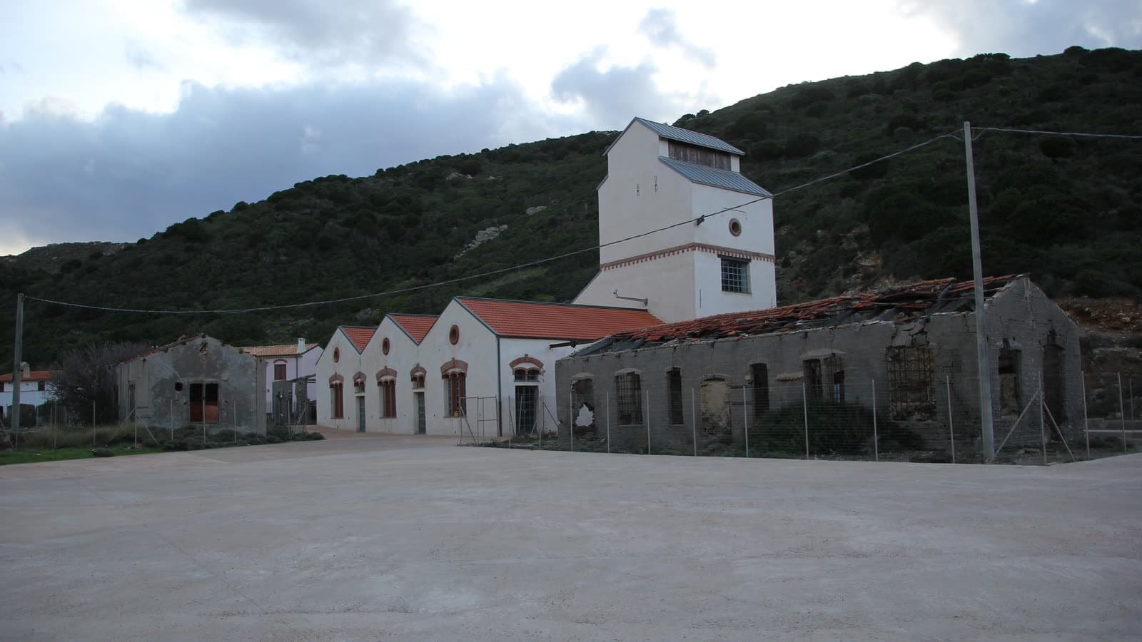 Il villaggio minerario abbandonato dell'Argentiera: la laveria e i capannoni in pietra sotto un fianco spoglio