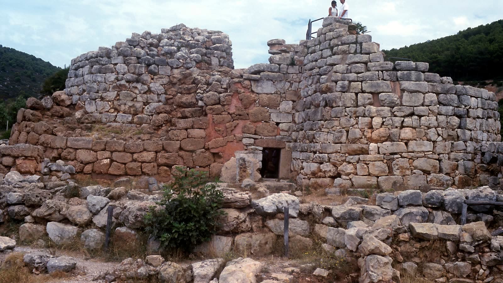 La torre centrale del nuraghe Palmavera vicino ad Alghero, muri a secco con visitatori in cima