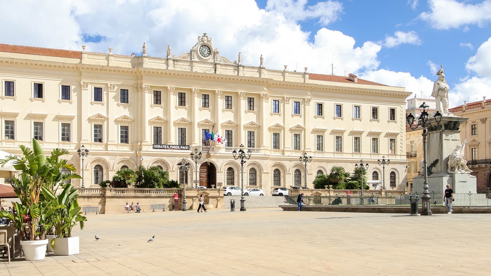 Piazza d'Italia a Sassari, il Palazzo della Provincia dietro le palme e un'ampia piazza pavimentata