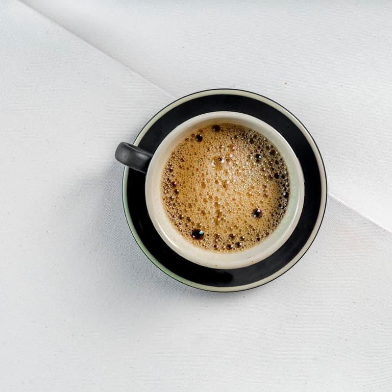 An espresso in a black-rimmed cup seen from above, crema on the surface