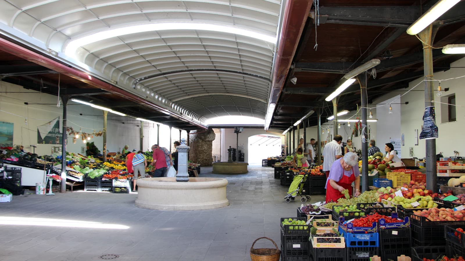 The covered market in Alghero: stalls of fruit and vegetables under a vaulted roof