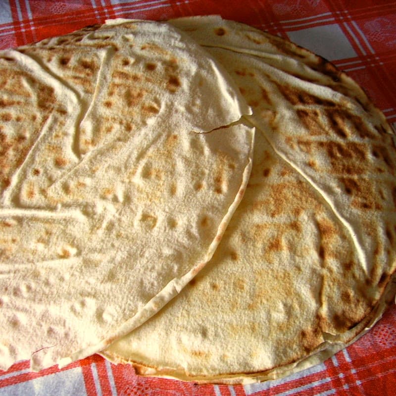 Round sheets of pane carasau stacked on a checked cloth