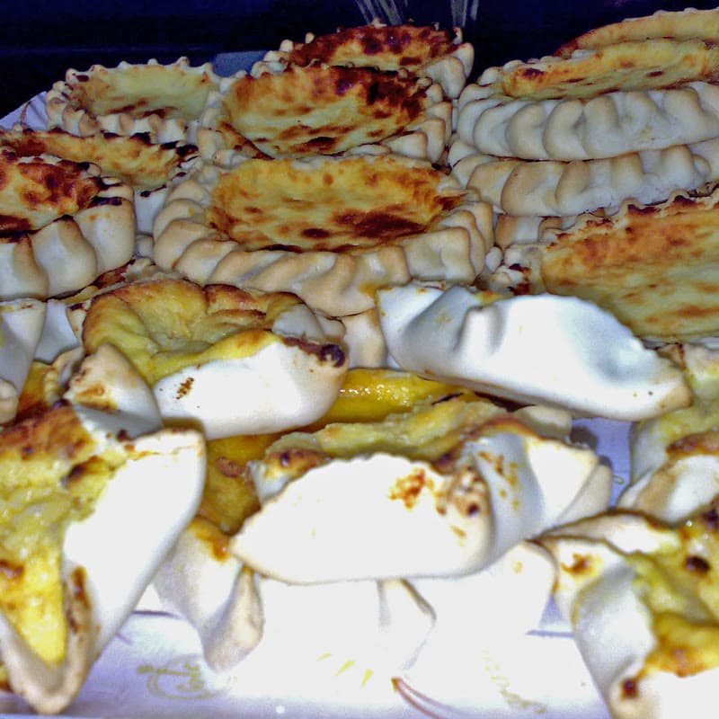 A tray of pardulas, open tartlets with a cracked cheese filling