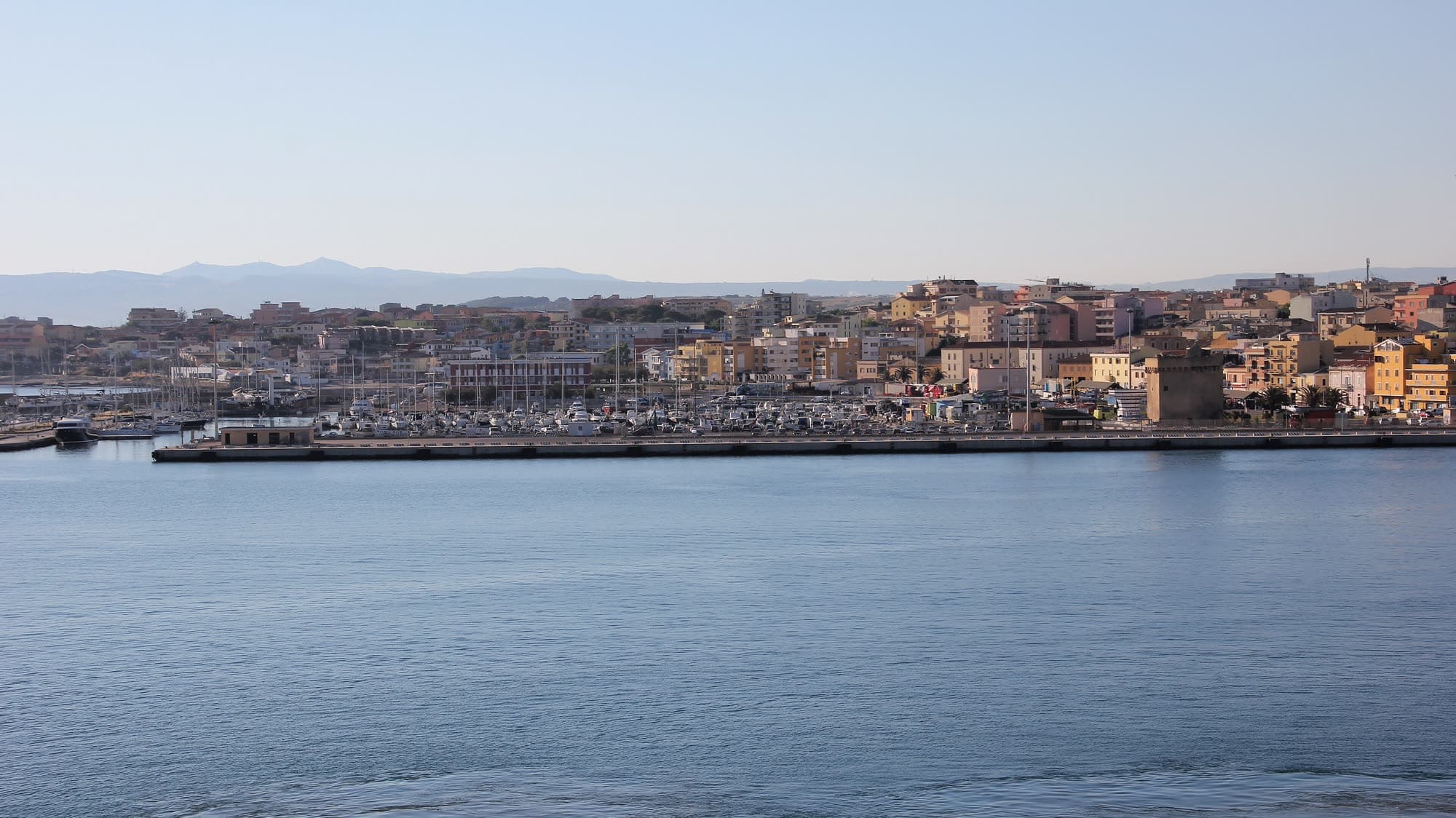 Porto Torres seen from the water: the breakwater, the marina and the town's low waterfront behind it