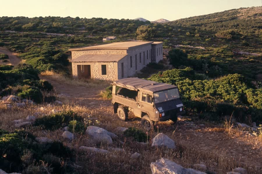 The old barracks of the Sr. 413 battery on Punta Giglio, with a weathered off-road vehicle parked in front.
