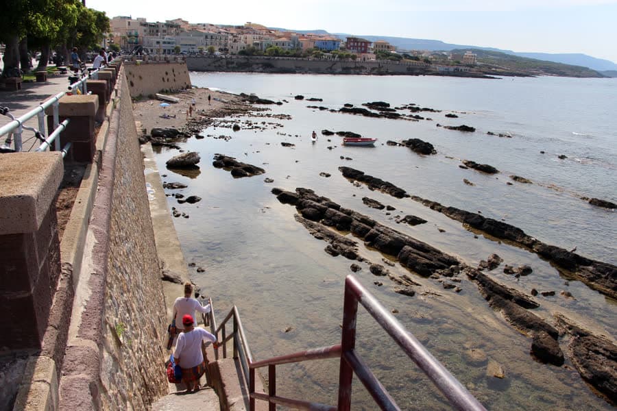 The paved walkway behind the Colombo seafront in Alghero, with steps down to flat rock and the sea.