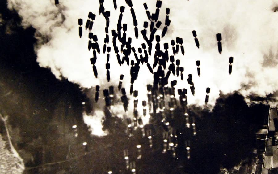 Schwarz-weiße Luftaufnahme fallender Bomben über dem Flugfeld Monserrato bei Cagliari im Jahr 1943