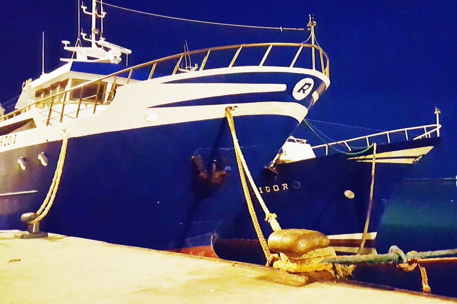 The bow of a working fishing boat moored at a quay.